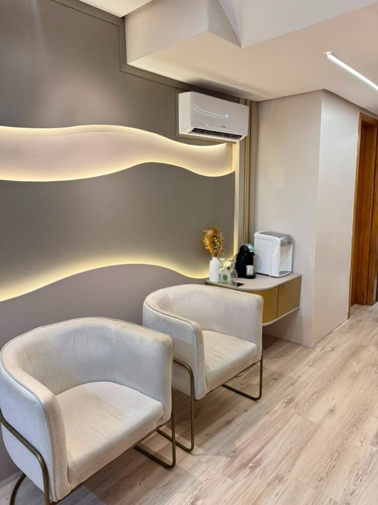 Recepção do estúdio com poltronas claras e parede iluminada